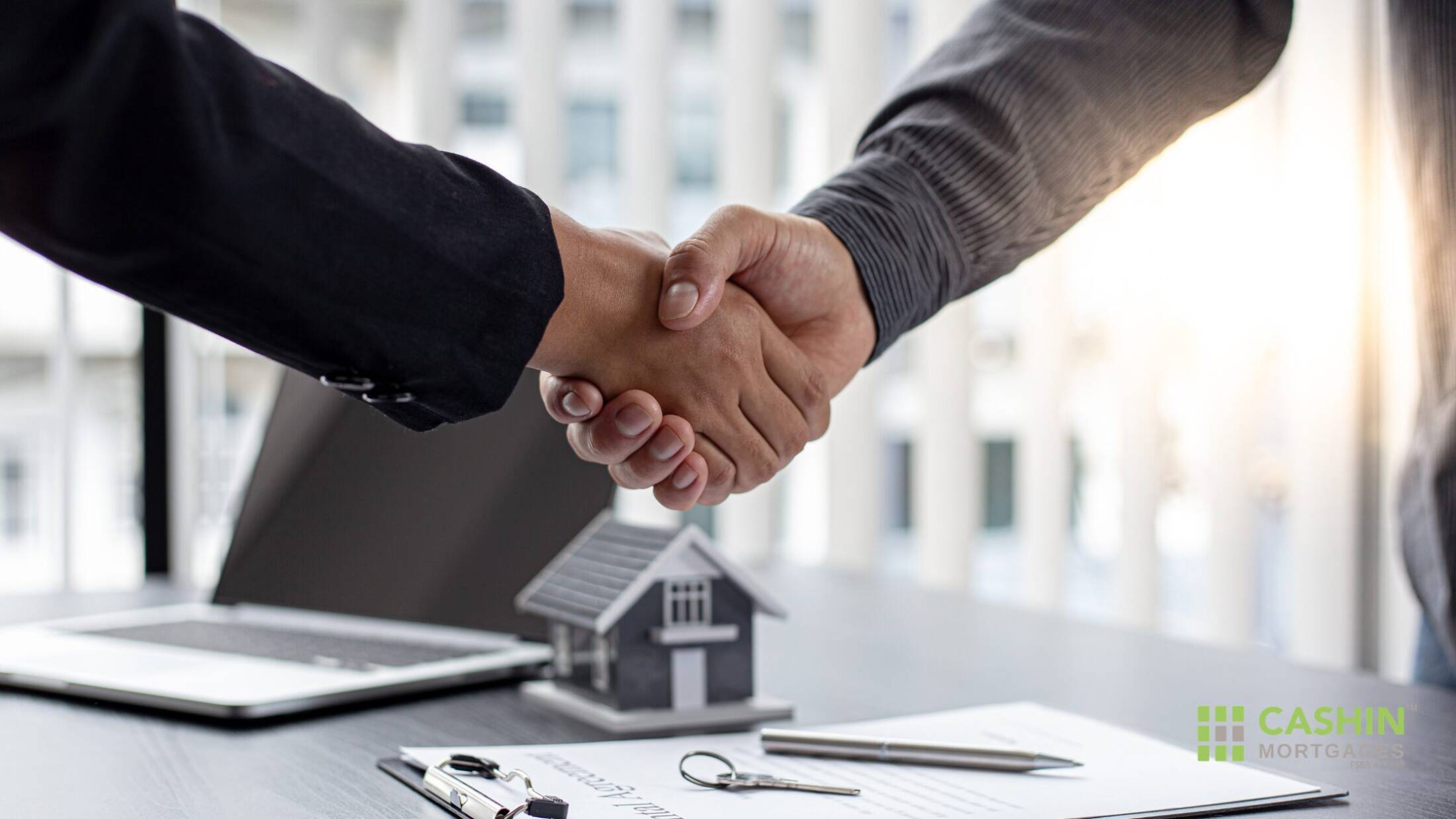 Handshake between two people during a home property agreement with house keys and documents